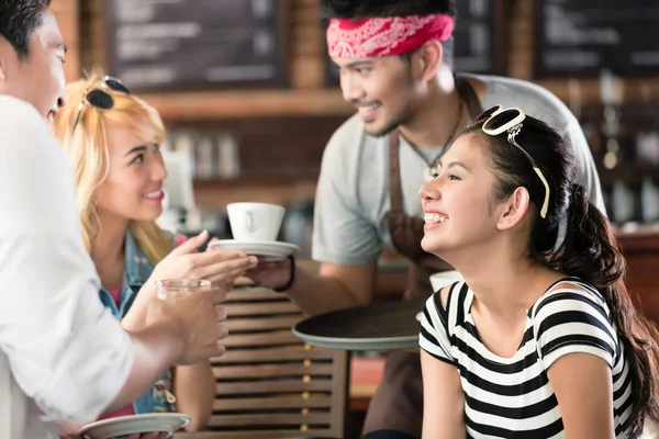 Waiter serving coffee in Asian cafe to women and man — Stock Photo, Image