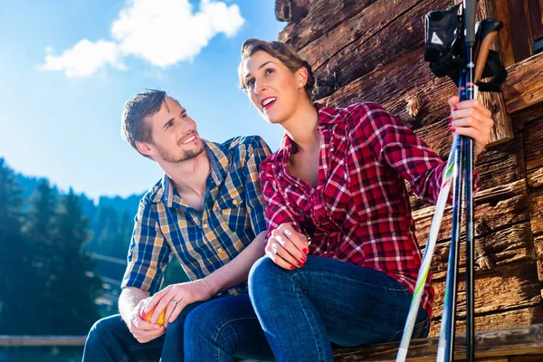 Casal descansando da caminhada nórdica na cabine da montanha — Fotografia de Stock