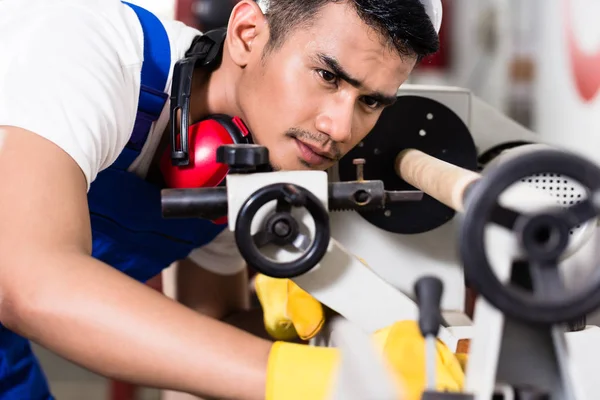 Worker adjusting turning machine in factory — Stock Photo, Image