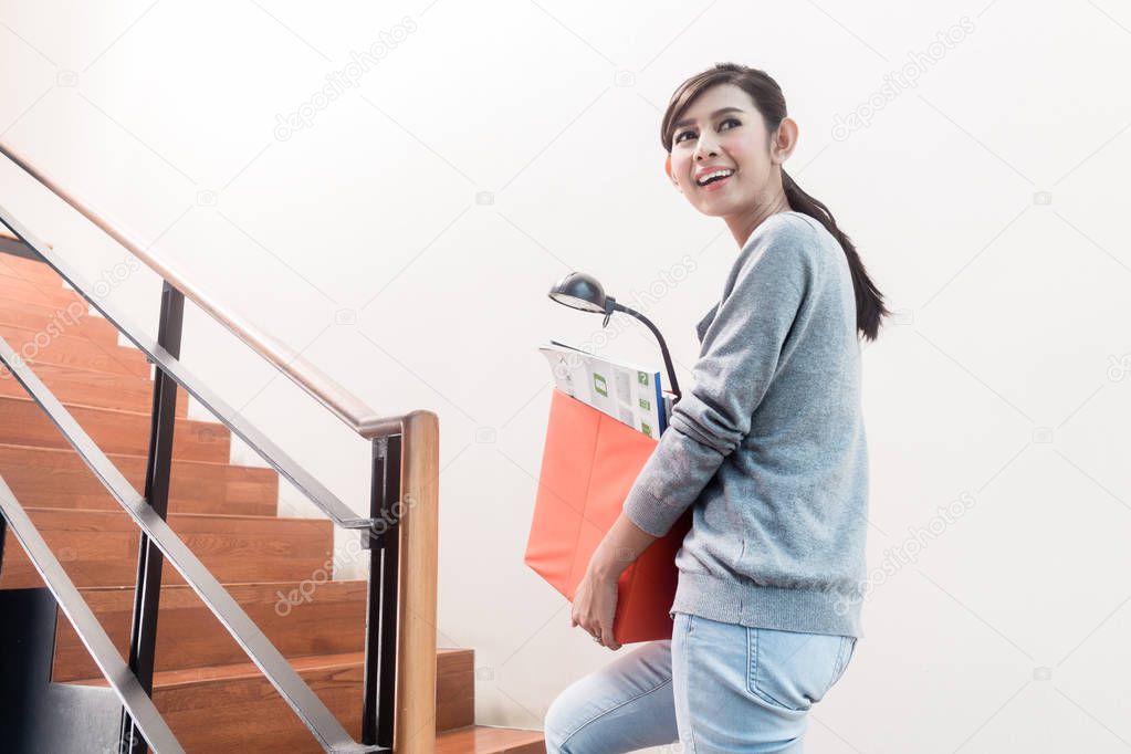 Young Indonesian girl carrying removal crate up the stairs