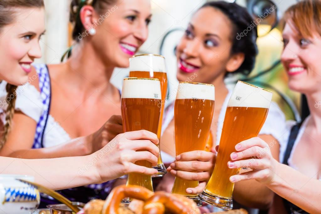Girls toasting with wheat beer in Bavarian pub