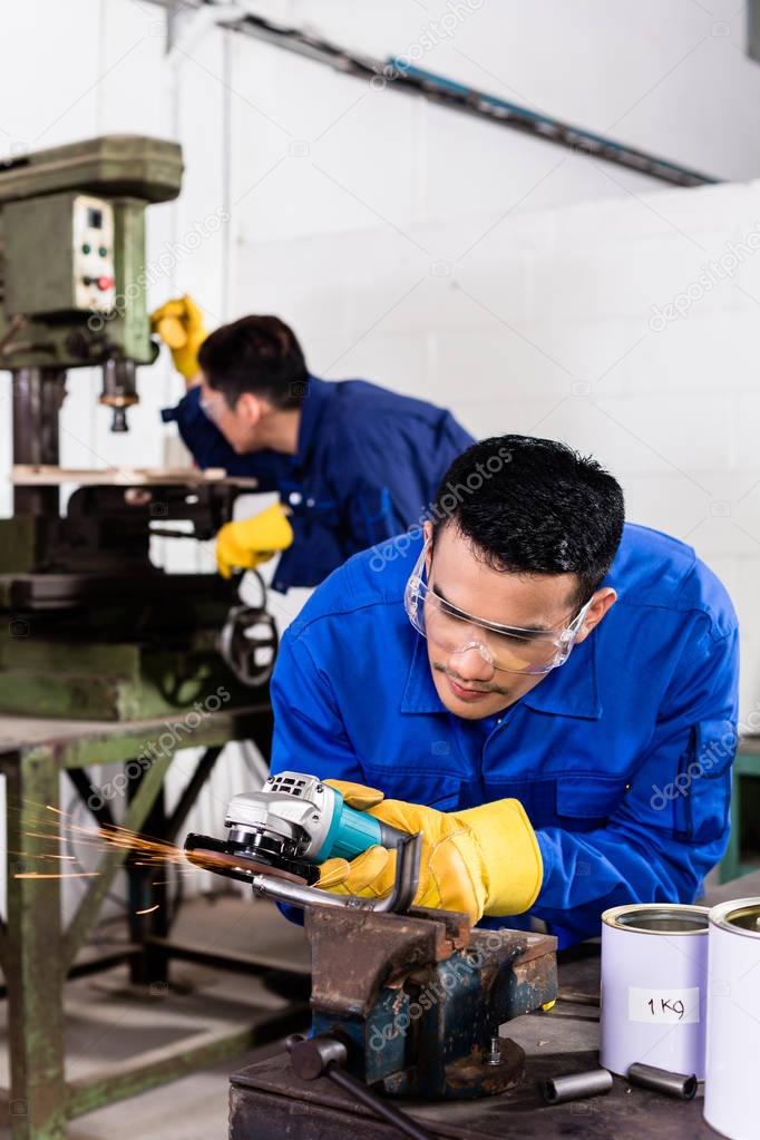 Metal workers in industrial workshop grinding