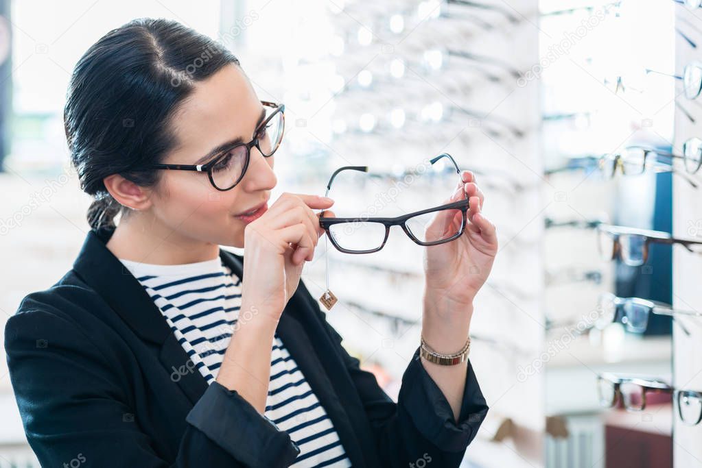 Woman taking glasses off shelf 