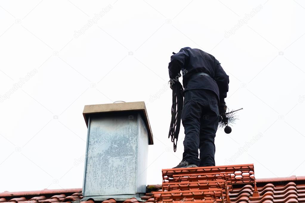 Chimney sweep on roof of home working