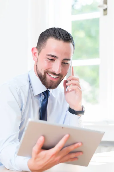 Affärsman i kontor med surfplatta och telefon — Stockfoto