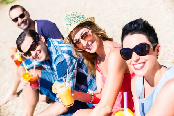 Czterech przyjaciół siedząc na plaży nad jeziorem z koktajle — Zdjęcie stockowe