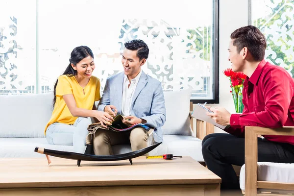 Couple with shop assistant in furniture store — Stock Photo, Image