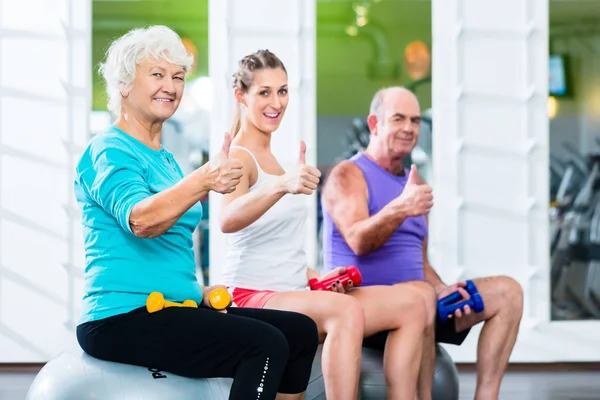 Senioren met trainer in de sportschool op sport opheffing barbell — Stockfoto