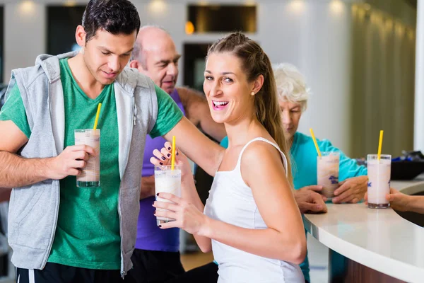 Pessoas bebendo batidos de proteína no ginásio de fitness — Fotografia de Stock