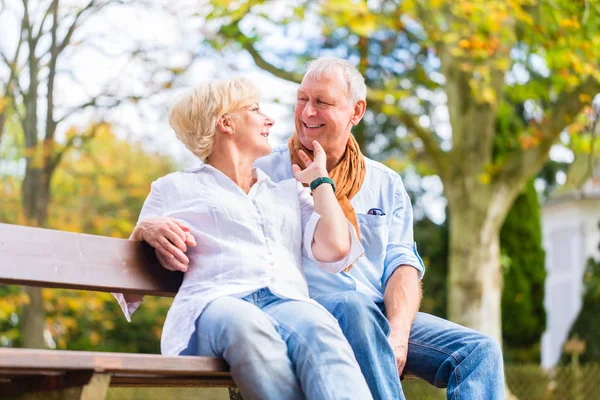 Seniorenpaar sitzt im Herbst auf Bank — Stockfoto