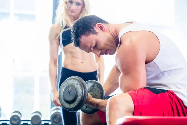 Casal em ginásio fitness com halteres levantar peso — Fotografia de Stock