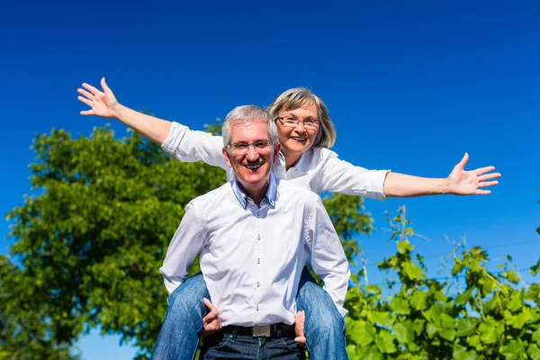 Senior Mann trägt Frau huckepack — Stockfoto