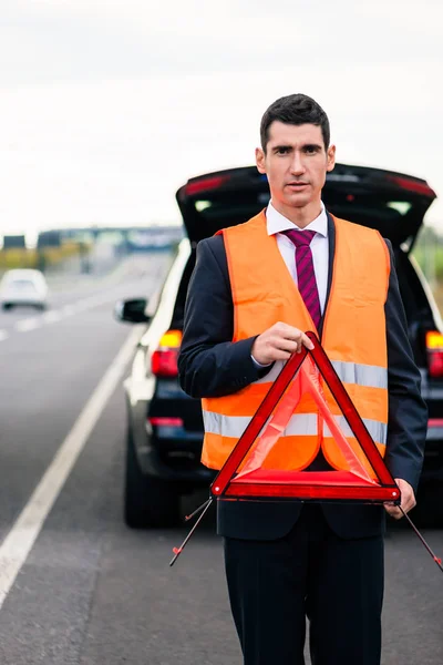 車の故障の警告の三角形を建てる男 — ストック写真