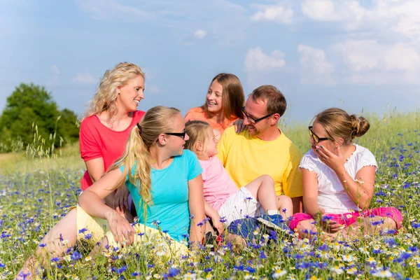 Familia sentada en el prado en flores — Foto de Stock