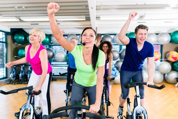 Grupp män och kvinnor som snurrar på fitness cyklar i gymmet — Stockfoto
