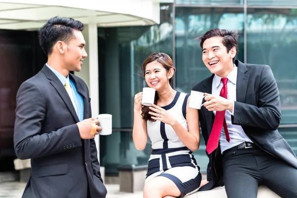 Asian businesspeople drinking coffee outside — Stock Photo, Image