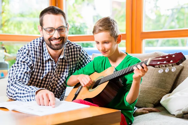 Père et fils jouant de la guitare à la maison — Photo