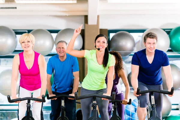 Grupo de hombres y mujeres girando en bicicletas de fitness en el gimnasio —  Fotos de Stock
