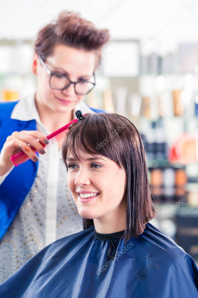 Hairdresser cutting woman hair in shop