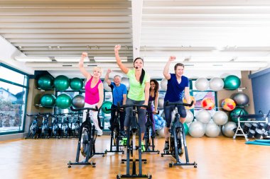Grup salonunda fitness bisiklet üzerinde iplik kadın ve erkek