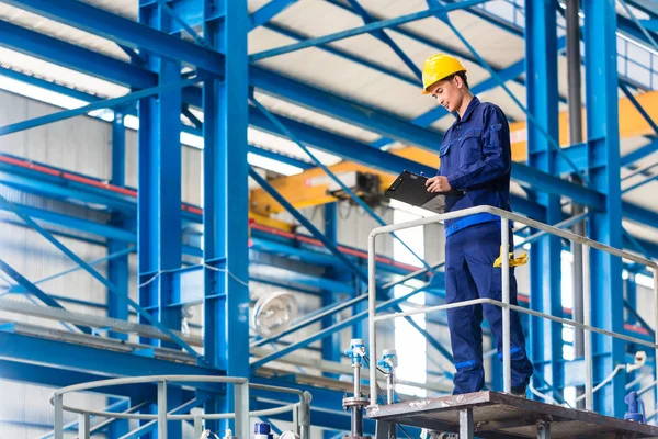 Trabalhador em grande oficina de metal verificando o trabalho — Fotografia de Stock