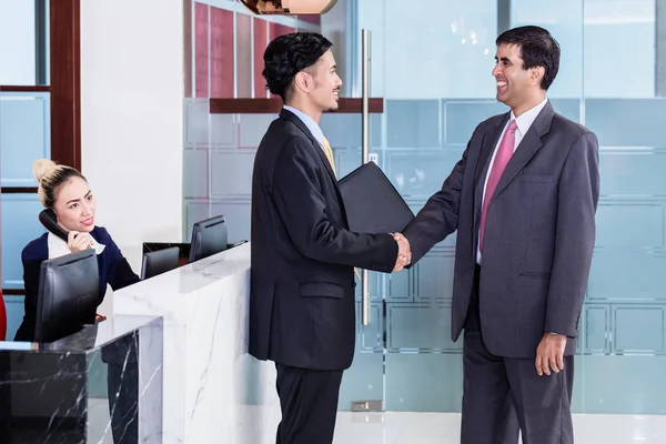 Manager welcoming business associate in office lounge