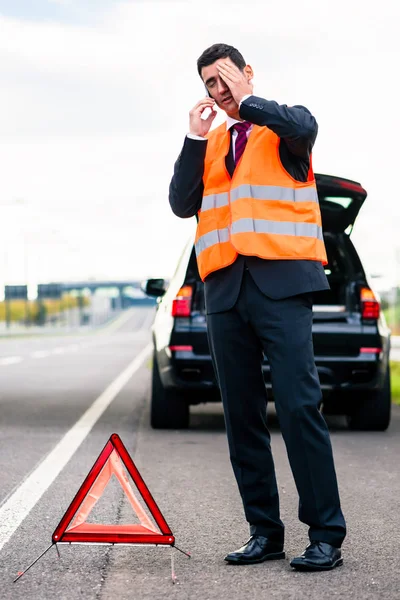 Mann mit Autopanne stellt Warndreieck auf — Stockfoto