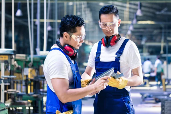 Азиатские рабочие проверяют заготовки на заводе — стоковое фото