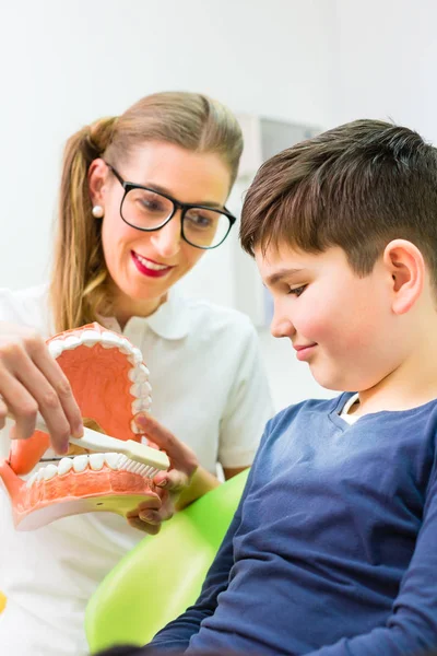 Tandarts uitleggen jongen schoonmaak tand — Stockfoto