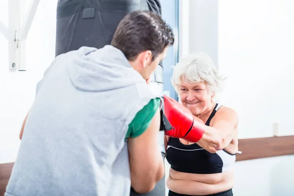 Seniorin mit Trainer im Boxsparring — Stockfoto