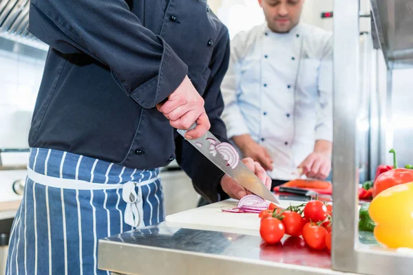 Cocineros cocinando y cortando verduras y tomates — Foto de Stock