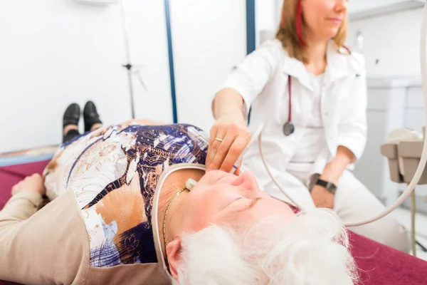 Médico examinando paciente mayor con ultrasonidos — Foto de Stock