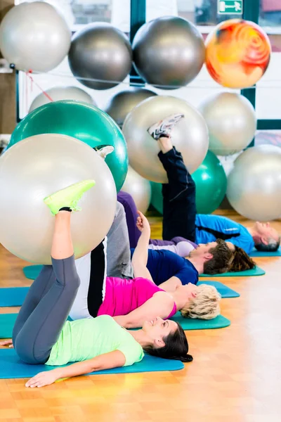 Jeunes et seniors faisant de l'exercice avec ballon dans la salle de gym — Photo
