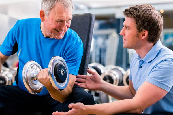 Starszy mężczyzna i trener w ćwiczenia w siłowni — Zdjęcie stockowe