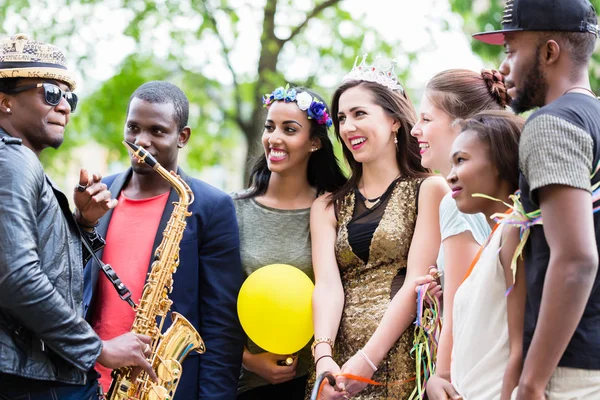 Straßenkünstler spielt Saxofon für multi-ethnische Gruppe — Stockfoto