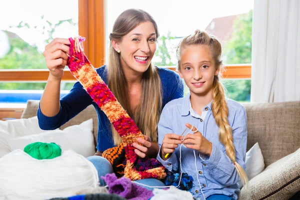 Mother teaching daughter knitting