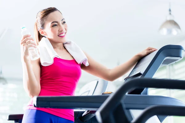 Smiling woman on treadmill presenting water bottle — Stock Photo, Image