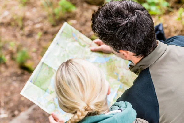 Senderistas doblando sobre mapa de senderos — Foto de Stock