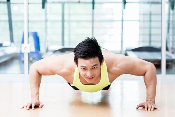 Muscular Asian man doing pushups in gym — Stock Photo, Image