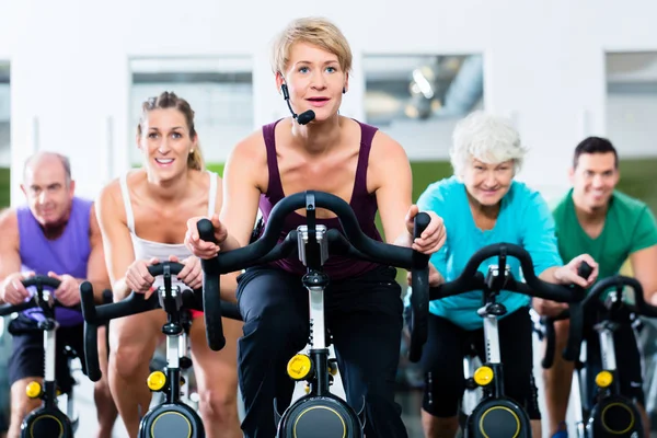 Pessoas idosas no ginásio girando em bicicleta fitness — Fotografia de Stock