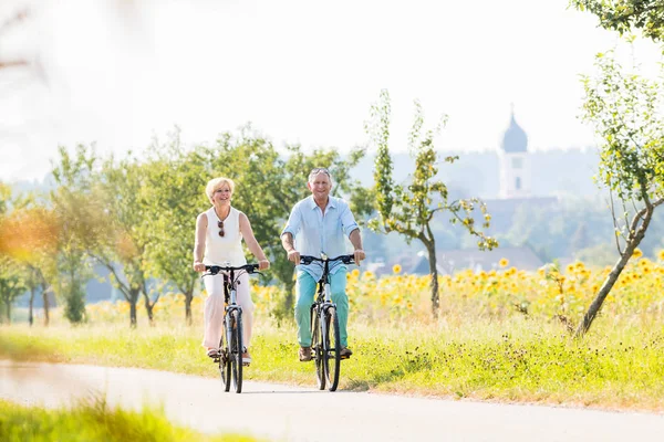 Idős pár, nő és férfi, bicikliznek — Stock Fotó