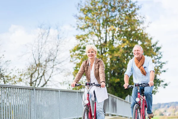 Senior couple with bicycles on bridge — Stock Photo, Image