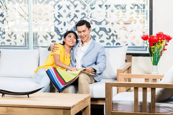 Asian couple buying sofa in furniture store
