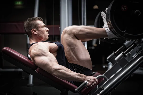 Homem em treinamento de ginástica na perna imprensa — Fotografia de Stock