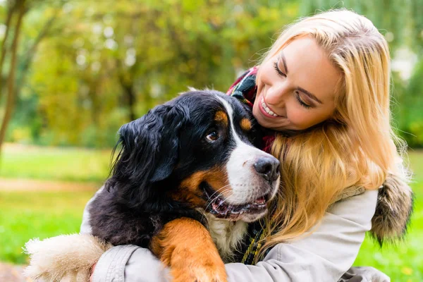 Kvinna som omfamnar hennes hund i höst park — Stockfoto