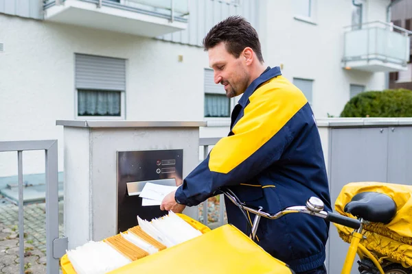 Postman delivering letters to mailbox — Stock Photo, Image