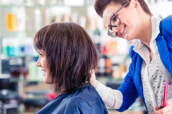 Coiffeur coupe cheveux femme dans le magasin — Photo