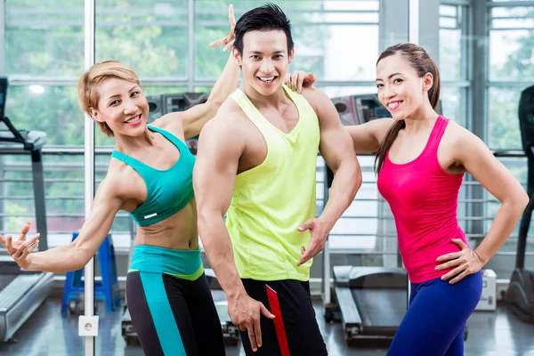 Hombre muscular entre dos mujeres deportivas pose llamativa — Foto de Stock