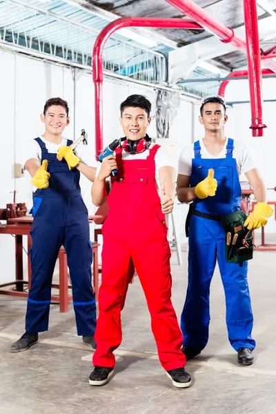 Три азиатских промышленных рабочих гордятся фабрикой — стоковое фото