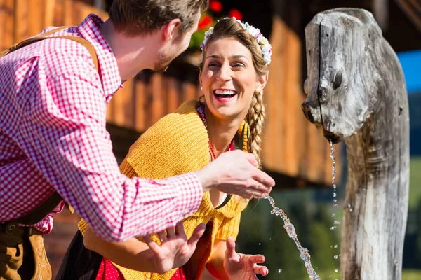 Couple at mountain hut drinking water from source — Stock Photo, Image